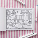 Open coloring book page of a pig riding a San Fransisco trolley car.